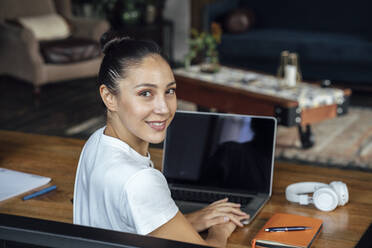 Lächelnde Geschäftsfrau mit Laptop auf dem Schreibtisch - VPIF04992