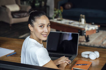 Smiling businesswoman with laptop on desk - VPIF04992