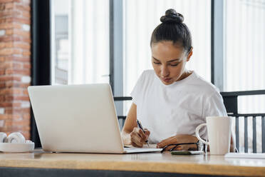 Berufstätige Frau beim Schreiben mit Laptop am Schreibtisch sitzend - VPIF04994