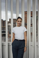 Smiling businesswoman with hand in pocket standing on terrace - VPIF05029