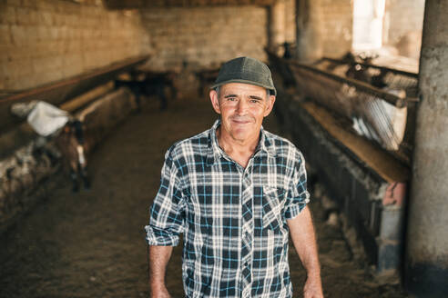 Smiling male goat herder standing in shed - GRCF00892