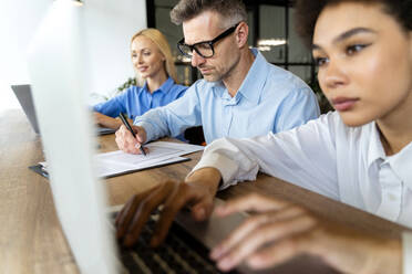 Geschäftsmann arbeitet mit weiblichen Angestellten im Büro - OIPF01121