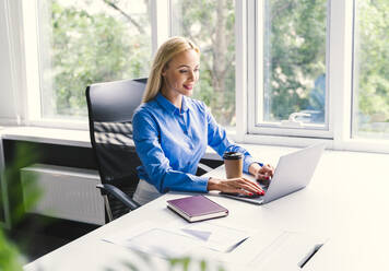 Blonde Geschäftsfrau mit Laptop bei der Arbeit im Büro - OIPF01143