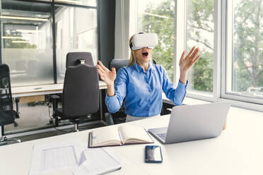Überrumpelte Geschäftsfrau trägt Virtual-Reality-Headset im Büro - OIPF01162