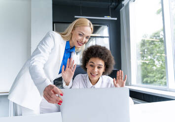 Smiling female business professionals attending video call through laptop in office - OIPF01181