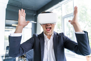 Businessman screaming while wearing virtual reality headset in office - OIPF01211