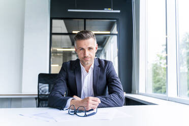 Male business person sitting at desk in office - OIPF01212