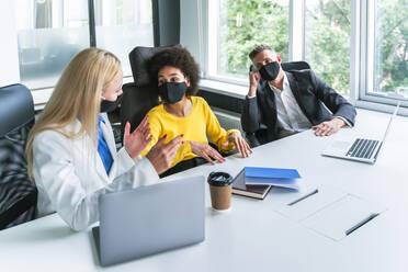 Male and female business colleagues discussing in office during COVID-19 - OIPF01231