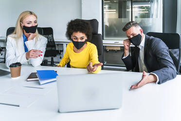 Multiethnische Geschäftsleute diskutieren am Laptop im Büro - OIPF01232