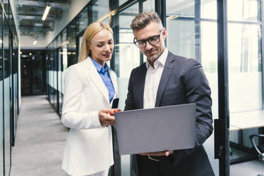 Businesswoman discussing with male colleague on laptop in office - OIPF01247