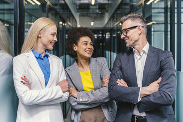 Happy male and female business colleagues standing with arms crossed at office - OIPF01260