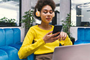 Businesswoman using wireless technologies in office lobby - OIPF01269