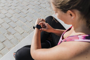 Sportswoman checking time on smart watch during sunny day - JRVF01857