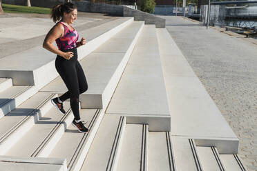 Sportlerin, die sich während eines sonnigen Tages auf einer Treppe abwärts bewegt - JRVF01862