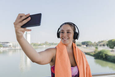 Sportlerin lächelt, während sie ein Selfie mit ihrem Mobiltelefon macht - JRVF01869