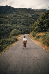 Mature woman wearing backpack walking on road - GRCF00907