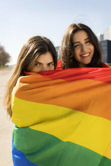 Junges lesbisches Paar mit Regenbogenfahne - VABF04339