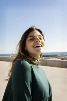 Happy woman with eyes closed during sunny day - VABF04359