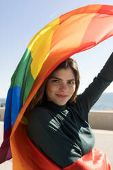 Lächelnde lesbische Frau mit Regenbogenfahne - VABF04364