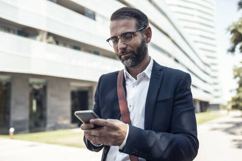 Businessman with eyeglasses using smart phone - JSRF01632