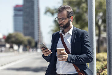 Male professional with disposable cup using mobile phone - JSRF01644