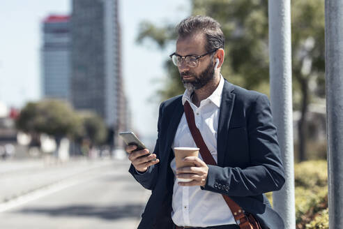 Männlicher Berufstätiger mit Einwegbecher und Mobiltelefon - JSRF01644