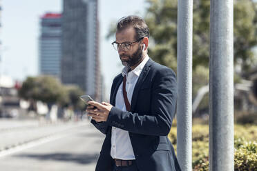 Bearded male professional using mobile phone on sunny day - JSRF01645