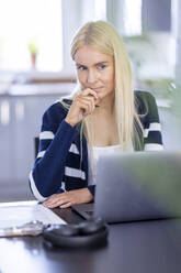 Nachdenkliche Geschäftsfrau mit Laptop bei der Arbeit zu Hause - WPEF05293