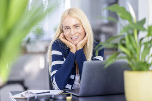 Lächelnde blonde Geschäftsfrau am Schreibtisch im Heimbüro - WPEF05304