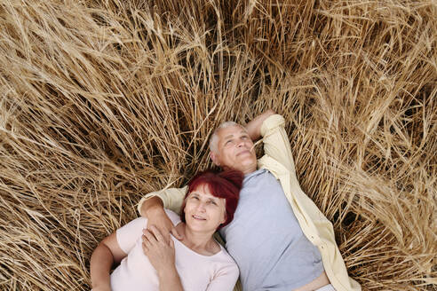 Älteres Paar entspannt sich auf einem Weizenfeld - EYAF01754