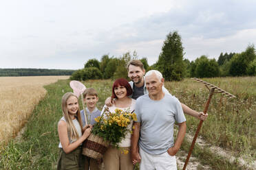 Glückliche Familie mit Blumen und Harke auf dem Feld - EYAF01758