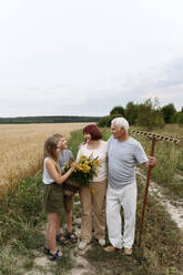 Kinder und Großeltern mit Blumen auf dem Feld - EYAF01759