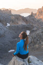 Junge Touristin, nachdenklich auf einem Felsen, Picos de Europe, Kantabrien, Spanien - JAQF00773