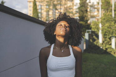 Afro-Frau mit dem Kopf an der Wand genießt die Sonne - JCCMF03909