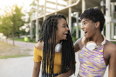 Cheerful young women laughing while looking at each other - JCCMF03935