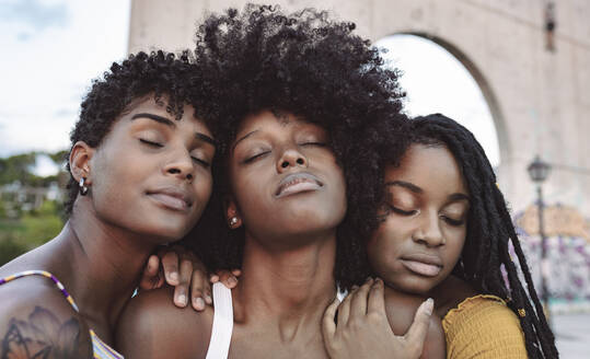 Young women with eyes closed leaning on shoulder's of female friend - JCCMF03973