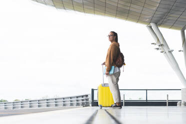 Woman with luggage standing at airport - JAQF00791