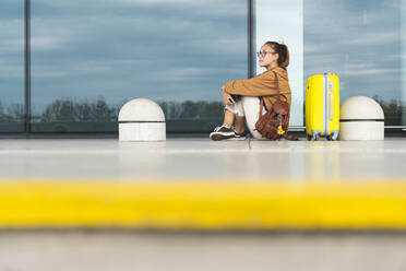 Junge Frau sitzt mit Gepäck am Flughafen - JAQF00801