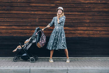 Frau mit Kinderwagen auf dem Gehweg stehend - OMIF00072