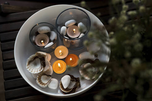 Bowl of burning candles and pebbles with seashells - LLUF00104