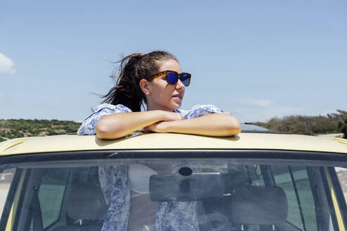 Mittlere erwachsene Frau lehnt sich an einem sonnigen Tag durch das Schiebedach eines Lieferwagens - PGF00821