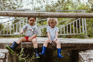 Junge sitzt mit Freund beim Angeln auf einem Steg - MRRF01561