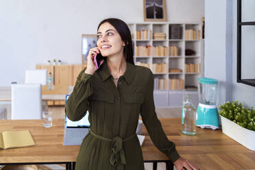 Female freelancer talking on mobile phone at home - GIOF13622