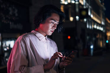 Handsome young man surfing net through mobile phone in city - AMWF00019