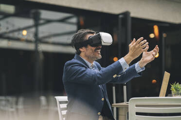 Smiling businessman gesturing while using wearable computer at hotel - JCCMF04001