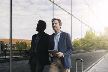 Male professional with digital tablet leaning on glass - JCCMF04022