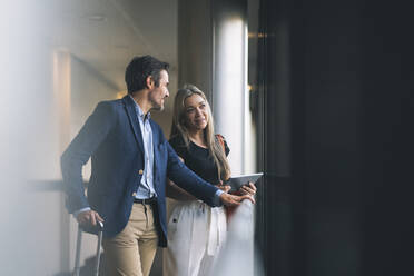 Smiling businesswoman and male professional talking in hotel - JCCMF04026