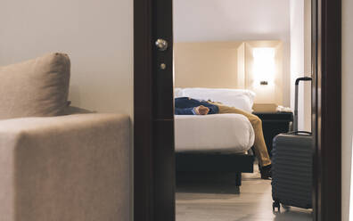 Geschäftsmann entspannt auf dem Bett im Hotelzimmer - JCCMF04030