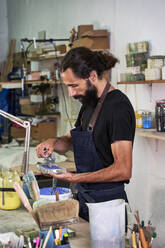 Male craftsperson coloring concrete while standing at workbench - VEGF05038