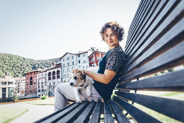 Frau mit Hund auf einer Bank an einem sonnigen Tag - OMIF00095